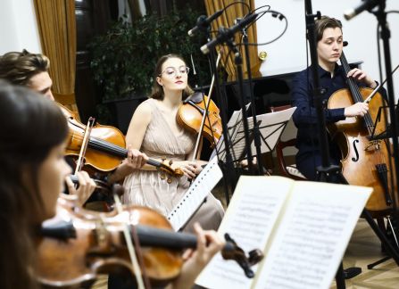 A photograph. A string concert in Villa Decius. The musiacians play the violin and the cello.